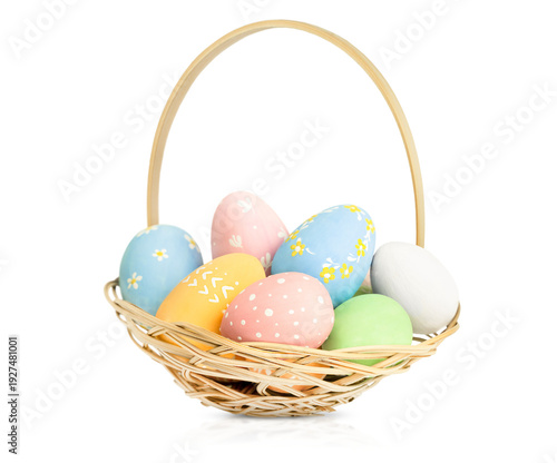 painted Easter eggs in a wicker basket on a white isolated background