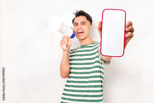Foto Excited Asian man shouting into megaphone while holding blank smartphone screen against white background to announce seasonal sales or big promotional news
