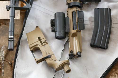 Tactical rifle parts assembly on table for firearm gunsmithing and weapon maintenance. An upper receiver, lower receiver and magazine ready for detailed build