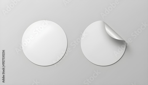Blank white round adhesive stickers are perfectly arranged on a minimalist light gray background, offering a versatile template for product branding and design mockups, with one sticker featuring a re