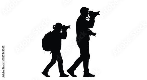 Two photographers walking one adult and one child in stark black silhouette