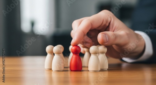 Hand selecting a single red wooden figure among many beige ones