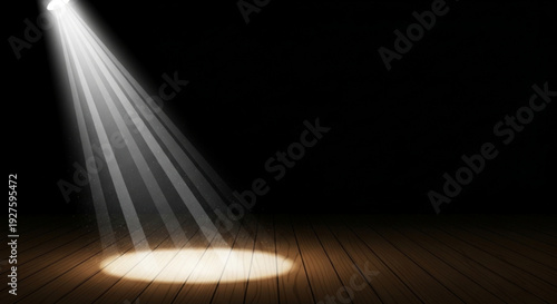 Spotlight shines down on wooden stage floor in darkness highlighting empty performance space with dramatic lighting effect