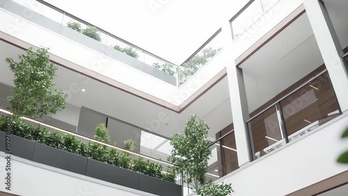Contemporary commercial building atrium featuring multiple floors, internal balconies, and lush indoor greenery, creating a sustainable and natural work environment