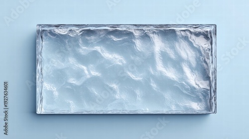 A stunning rectangular ice block glistens against a cool, light blue backdrop, showcasing its unique texture.