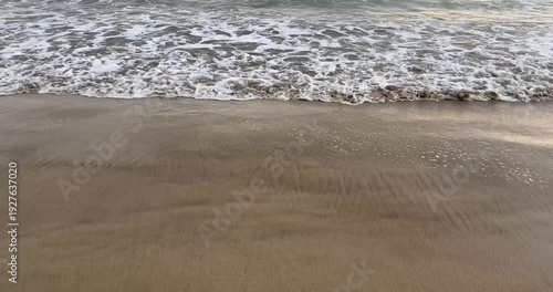 Serene beach scene with gentle waves on sandy shore.