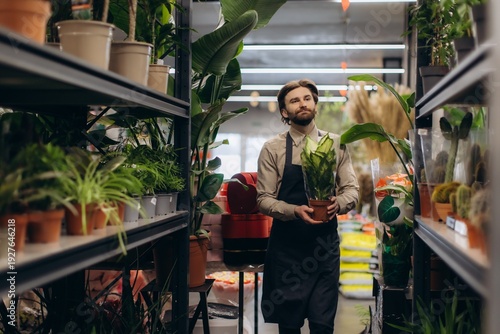Florist standing in plant shop holding potted plant