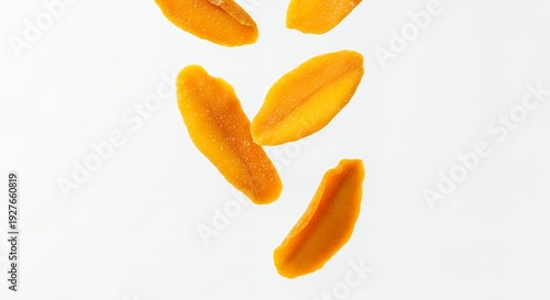 Dehydrated mango slices falling against a clean white background for healthy snacks
