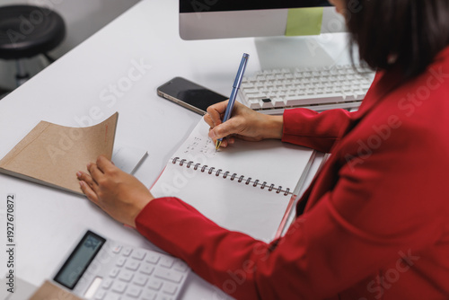 Woman writing notes in notebook at modern office desk