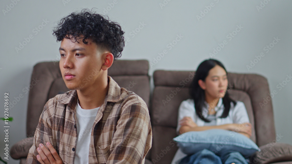 Obraz premium Young Asian Couple in Conflict Sitting on Brown Couches in Living Room