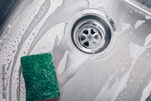 Fotografie Cleaning a Kitchen Sink with Sudsy Water and a Green Scrubber Sponge