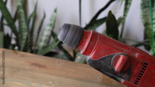 A red electric drill with a black chuck spins, showcasing tool operation for construction and renovation work in a home setting.