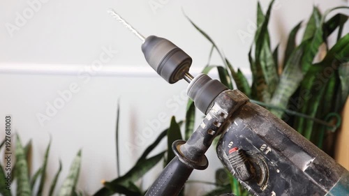 Close up of a power hammer drill with a drill bit in motion for construction work. Maintenance tool for home repair and renovation.