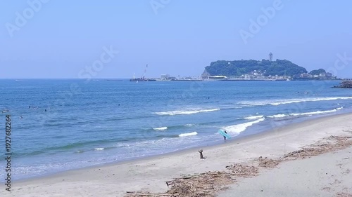 サーファーが波と戯れる夏真っ盛りの湘南・鎌倉の海と、美しい江ノ島の風景で、夏休みのイメージ

