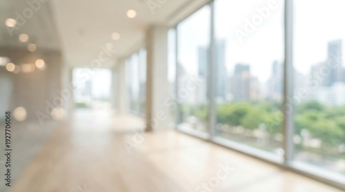 A softly focused, bright interior view of an empty modern office hallway or corridor with large windows offering a blurred city skyline background.