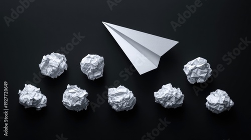 Paper airplane soaring above crumpled paper balls on a dark background.