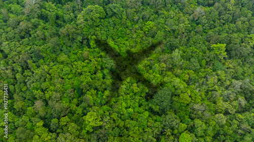 Fotografie Top view of a large airplane shadow gliding over a lush green tropical rainforest canopy, symbolizing air travel, adventure, and flight transit over nature