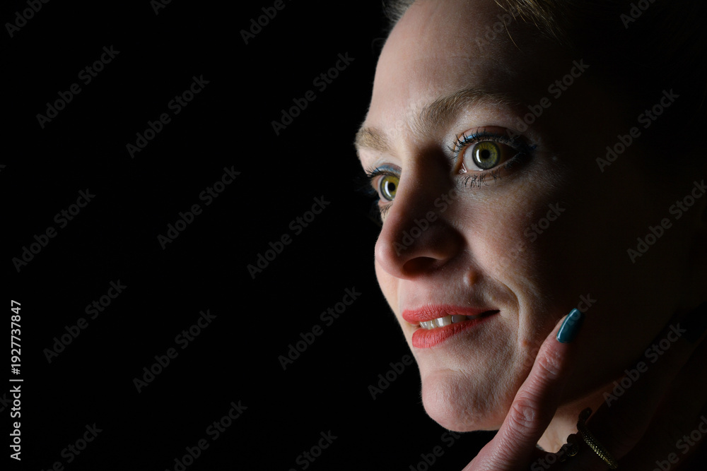 Naklejka premium Low-Key-Portrait eines Models im Mantel vor dunklem Hintergrund. Dramatisches Licht, starke Schatten und roter Lippenstift setzen elegante, ausdrucksstarke Akzente.