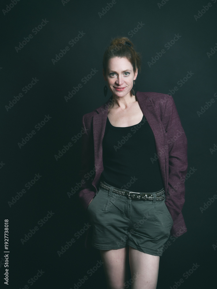 Obraz premium Low-Key-Portrait eines Models im Mantel vor dunklem Hintergrund. Dramatisches Licht, starke Schatten und roter Lippenstift setzen elegante, ausdrucksstarke Akzente.