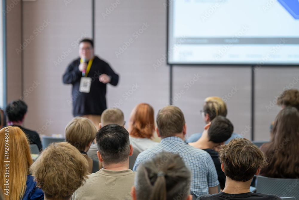 Obraz premium Lecturer presents to attentive audience in conference room with screen projection.