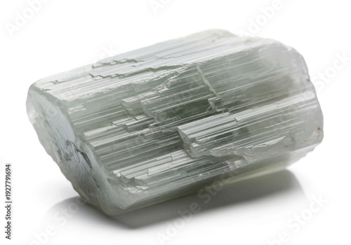 A close-up view of a raw crystal mineral specimen, showcasing its natural texture and structure on a plain surface from a slightly elevated angle