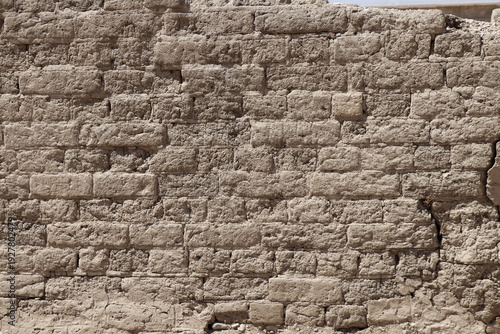 Old cracked adobe brick wall showing weathered texture outdoors
