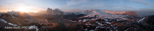 Aerial view of the sun's golden rays kiss the snow-capped peaks of the Dolomites, painting the landscape with warmth and serenity, Alpe di Siusi, Trentino-Alto Adige, Italy.