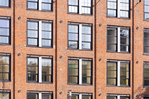 Historic red brick industrial building with large windows in an urban environment. Industrial style architecture with modern renovations under a clear sky
