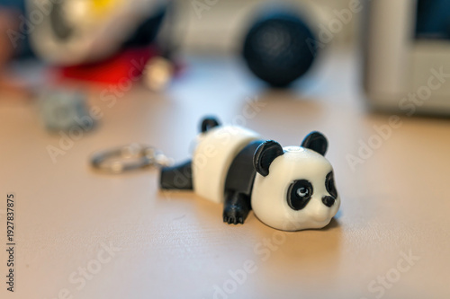 Panda keychain figure resting on a table with various items in the background