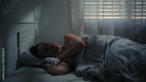 Tired woman waking up in bed feeling exhausted and unwell in the morning.