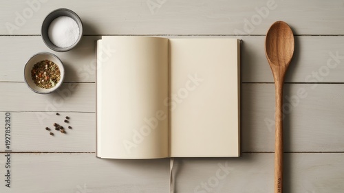 Open blank recipe book with spices and wooden spoon on a light wooden table