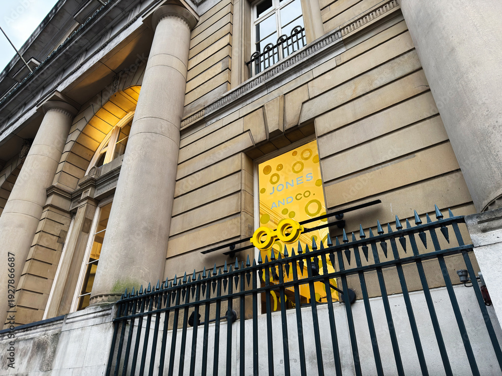 Naklejka premium Historic Manchester Jones And Co Styling Opticians office building with yellow signage and iron fence in front