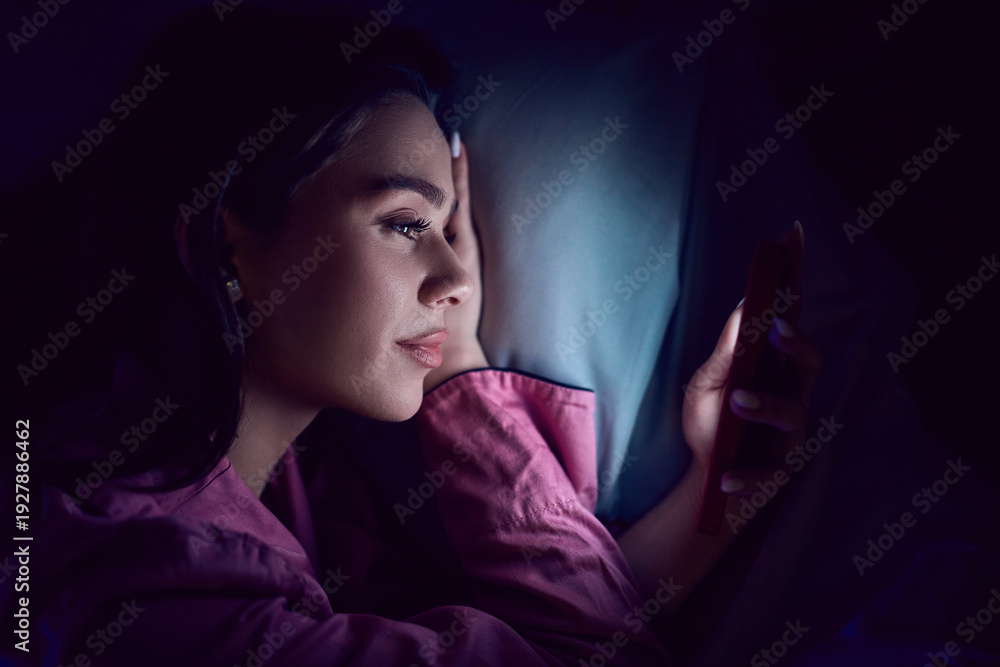 Fototapeta premium Close up of young woman using smartphone in dark bedroom. Concept of private messaging, mobile banking apps, secure login, digital privacy and individual screen time habits.