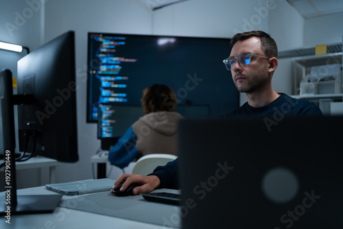 Foto Focused professional software engineer working on laptop and agentic terminal coding in a modern office