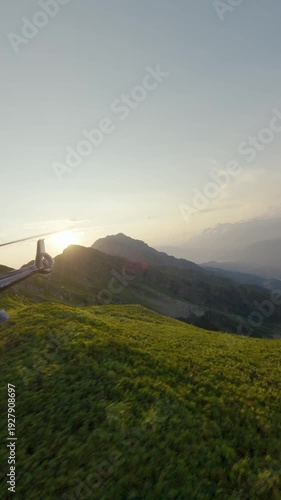 Vertical video. Modern aviation air transportation on greenery rock peak at cinematic natural sunrise valley FPV sport drone shot. Flying emergency extreme travel transport people bright sun highland