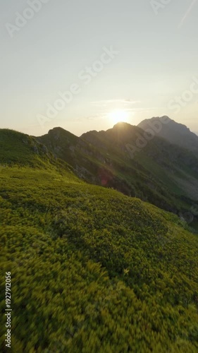 Vertical video. FPV drone man pilot in mask goggles standing on mount top near helicopter on sunset. Aerial view of tourist, mountainous valley. Tourism, travel, videographer work job