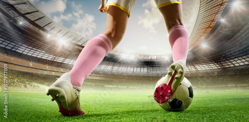 Obraz na plátně Low angle female football player stepping on ball stadium lights composition