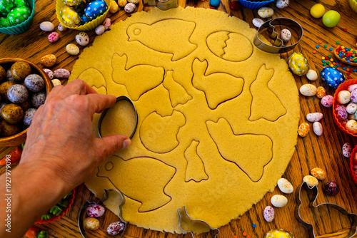 A woman carves Easter cookies in the shape of rabbits, eggs, and chicks. Traditional shortcrust pastries.
