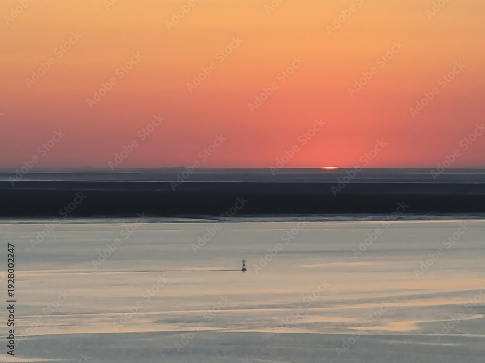 Obraz premium Bright sun descending over ocean at dusk