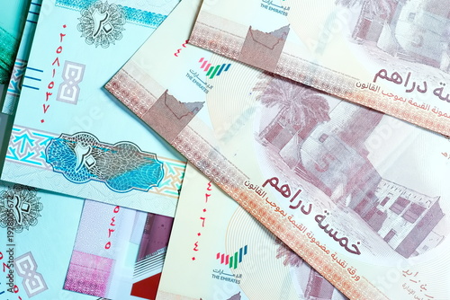 Close-up of United Arab Emirates Currency: AED Banknotes and Dirham Coins Scattered on Surface