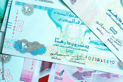 Close-up of United Arab Emirates Currency: AED Banknotes and Dirham Coins Scattered on Surface