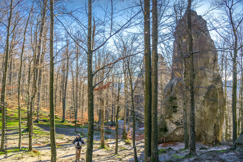Obraz premium Male hiker exploring sandstone rock formation in sunlit autumn forest landscape