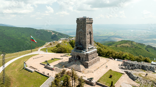 Aerial view Shipka Liberty Memorial monument Bulgaria. Historic stone tower mountain peak summer day. Stara Planina mountains clouds sky background. Bulgarian national landmark drone photography scene