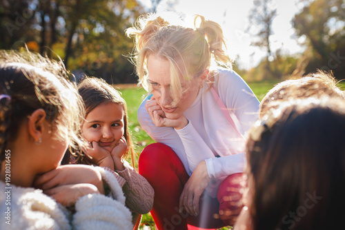 Female animator playing with a group of children at an outdoor birthday party.
