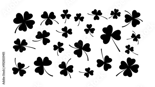 A collection of black four-leaf clovers scattered across a white background, representing luck and springtime