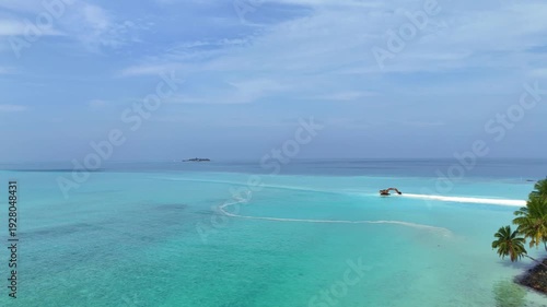 Aerial view of an excavator working on a white sandbank to extend the beach. Heavy machinery digging sand from the turquoise ocean for land reclamation. Maldives, Mathiveri.
