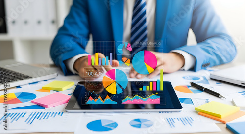 Businessman analyzing colorful data charts on digital tablet in modern office