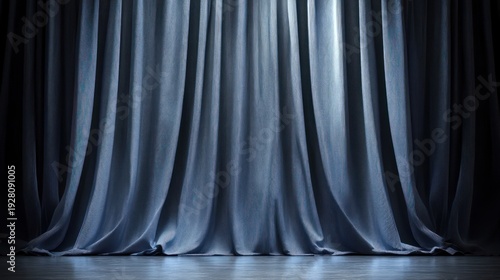 Dark gray drapes, lit from behind, hang in a theater