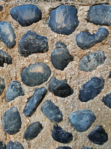 Dark round cobblestones embedded in a concrete base, showing the contrast of the decorative texture design on the playground floor
