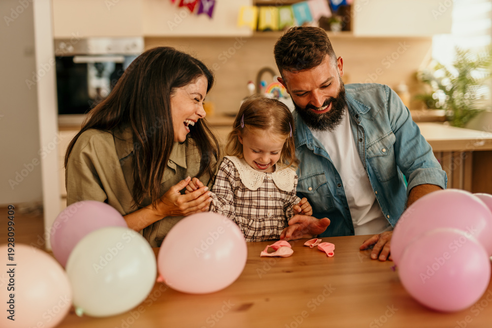 Fototapeta premium Parents celebrating child's birthday at home with balloons
